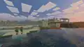 A desert village with Vibrant Visuals, during sunset. There is also some badlands on the right. The screenshot was taken in a river, so the yellow haze of the desert is not present. Instead, there is a blue haze, which makes the texture of the sand more visible.