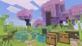 Copper golems near copper chests and regular chests in a cherry grove.