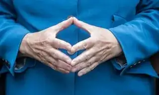 Merkel’s hands are in front of her stomach, the fingertips meet, the thumbs and index fingers form a quadrangular shape