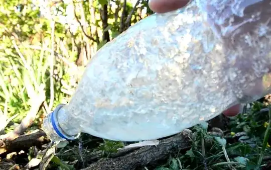 Ice particles have attached to the inside of the bottle as it is being emptied.