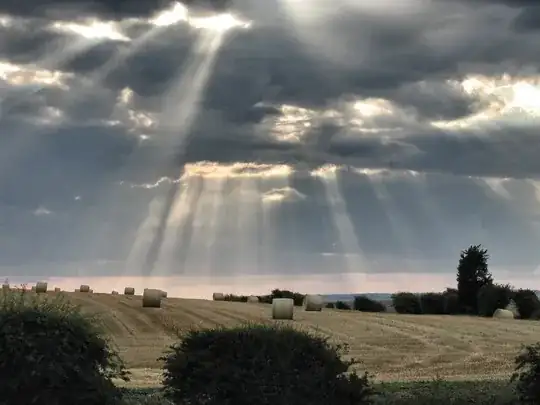 shafts of sunlight over field poking through clouds