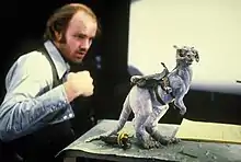 A photo of Phil Tippett observing a tauntaun miniature for stop-motion animation