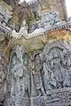 Relief of Hindu deities below lower eve and miniature decorative towers above it (below upper eve) in the Kedareshwara temple at Halebidu