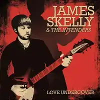 James Skelly holding a guitar with red background