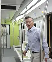 Macri walking into a new, colorful subway car