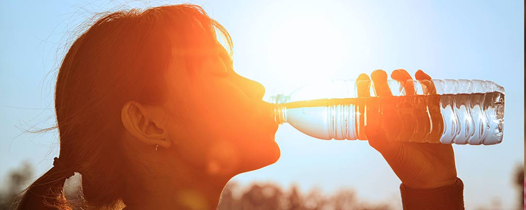 A woman drinking water in the summer heat.