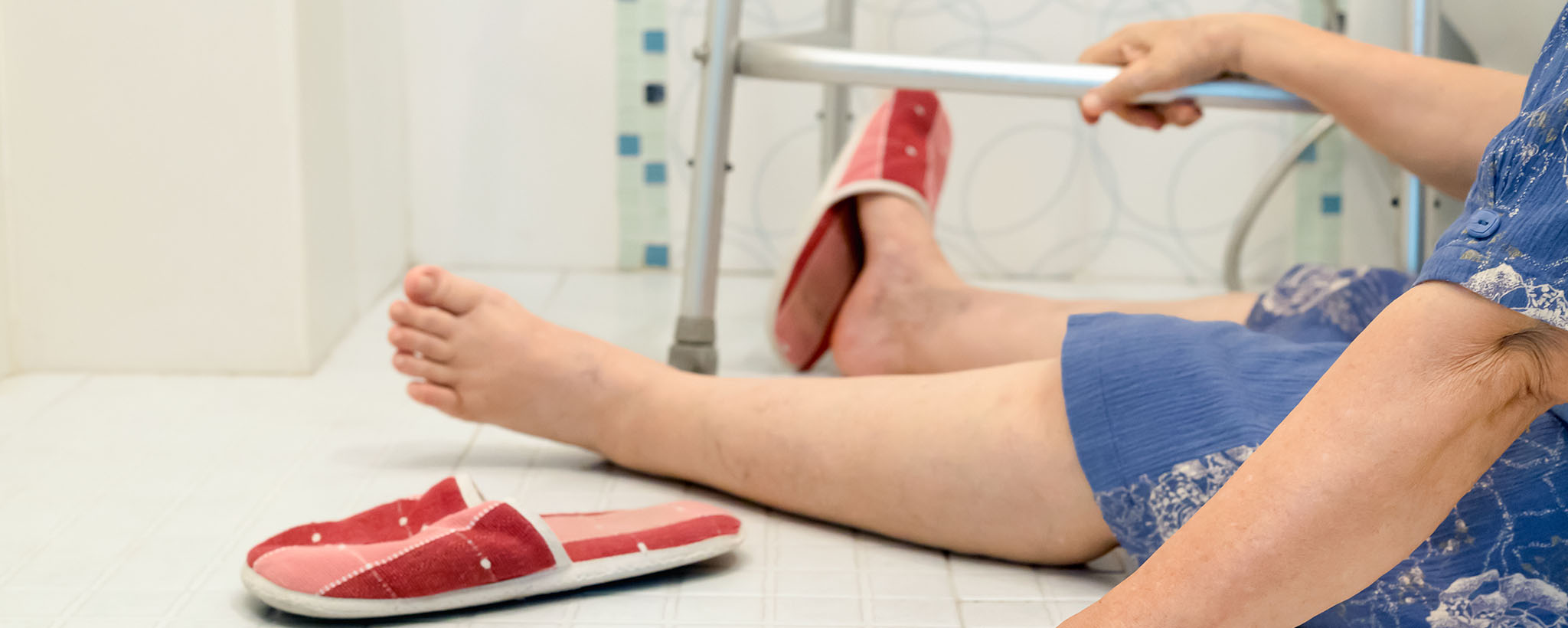 An elderly woman on the bathroom floor after falling.
