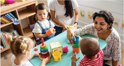 a teacher plays with young children at a table